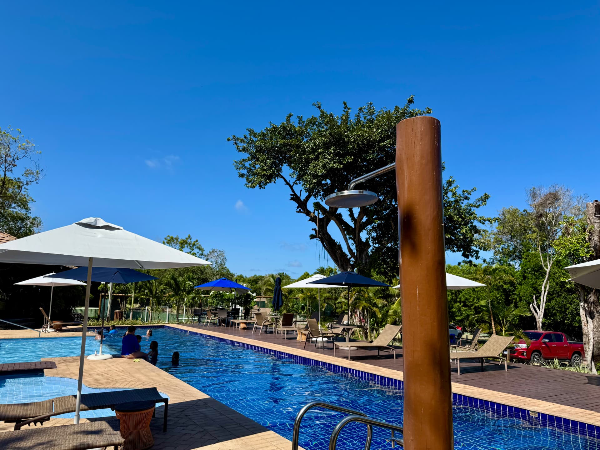 Deck da piscina com ducha e espreguiçadeiras
